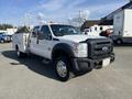 A 2015 Ford F-450 SD in white with a black grille and orange roof lights featuring a utility bed with tool compartments on the sides