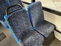 Blue and black patterned seats in a bus setting, featuring a backrest and armrest, designed for passenger comfort