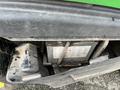 Close-up of the battery compartment on a 2014 John Deere 1585 Terrain Cut showing the battery with warning labels and dirt on the outer cover