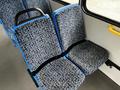 A pair of blue and patterned fabric bus seats with a sturdy black armrest between them