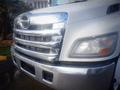 A white 2013 Hino 308 truck showcasing its chrome front grille and headlight design