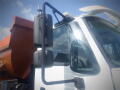 A 2016 International WorkStar 7500 truck with a large brown dump bed and a side mirror prominently displayed in the foreground