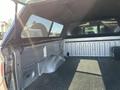 The image shows the interior of the bed of a 2014 Ford F-150 with a lined surface and a tool box in the corner