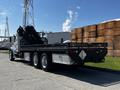 A 2012 Freightliner M2 112 flatbed truck with a black and silver color scheme featuring a large flatbed and two rear axles