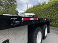 A 2011 International 4400 truck with a flatbed design featuring black paint and diamond plate elements alongside dual rear wheels