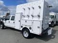 A 2015 Ford F-550 truck with a white utility body featuring multiple compartments and metal latches on the side