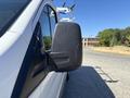 A white 2016 Ford Transit with a black side mirror parked on a road with equipment mounted on the roof