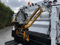 A 2014 Hino 195 with a yellow hydraulic lift mechanism attached to the rear for loading or unloading cargo