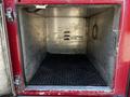 An empty compartment of a 2006 Emergency One Fire Truck with metal walls and a black rubber mat on the floor