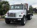 A white 1998 Freightliner FL80 truck with a flatbed and orange warning lights mounted on the cab