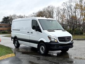 A 2017 Mercedes-Benz Sprinter van with a white exterior and black accents parked on a wet surface