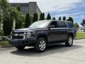 A 2017 Chevrolet Tahoe in dark color parked on the street featuring chrome accents and a spacious SUV design