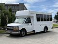 A white 2017 Chevrolet Express bus with a large windowed passenger area and a dark front grille parked on a driveway