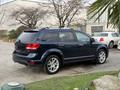 A blue 2013 Dodge Journey parked with a sleek design featuring alloy wheels and a spacious rear profile