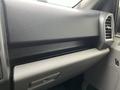 The interior dashboard of a 2016 Ford F-150 featuring a textured black surface with a storage compartment and air vents on the side