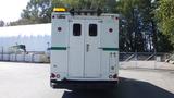 A 2004 Freightliner MT45 delivery truck viewed from the rear featuring a white exterior with a green stripe and a yellow light on the roof