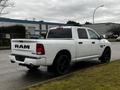 A white 2022 RAM 1500 Classic truck with black wheels and a slightly raised bed showcasing the RAM logo on the tailgate and 4x4 emblem on the rear quarter panel