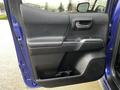 Interior door panel of a 2022 Toyota Tacoma featuring a handle armrest and storage compartment