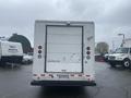 A white 2012 Ford Econoline cargo van viewed from the rear with a blank liftgate and tail lights visible