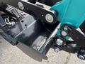A close-up view of the attachment mechanism of a 2024 AGT Industrial Green QH13R Mini Excavator showing metal components and a small bucket attachment