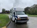 A 2015 Chevrolet Express van designed for accessibility featuring a ramp and equipped with a blue stripe along its side