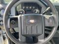 Steering wheel of a 2013 Ford F-250 SD with control buttons and a branded logo in the center