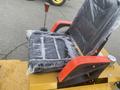 A black seat covered in plastic wrap with red armrests on a yellow mini loader designed for 2024 AGT KRW 23 model