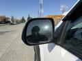 A 2015 Toyota Tacoma with a focus on the driver's side mirror reflecting a person standing nearby