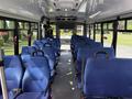 Interior of a 2020 Chevrolet Express bus featuring blue seats arranged in rows with safety straps and a view of the front dashboard