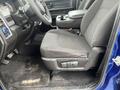 A driver's side interior view of a 2019 RAM 1500 Classic featuring a black fabric seat and a center console with storage compartments