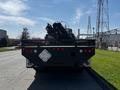 A 2012 Freightliner M2 112 truck in the foreground with a hydraulic boom and equipment mounted on the back