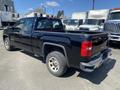 A black 2014 GMC Sierra 1500 pickup truck parked in a lot with visible bed and rear tires showing