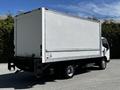 A 2018 Hino 195 box truck with a white cargo area and black chassis parked with the rear facing the viewer