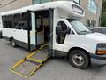 A 2017 Chevrolet Express shuttle bus with a ramp deployed for accessibility features large side doors and a spacious interior designed for passenger transport