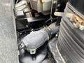 Close-up of an engine component from a 2008 Mitsubishi Fuso FE180 showing an air intake system with a black hose and various metal parts