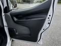 The interior door panel of a 2020 Nissan NV200 with a black handle and window control buttons