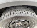The image shows a close-up of a tire mounted on a black wheel featuring a detailed tread pattern and visible lug nuts