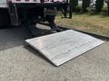 A 2015 Freightliner M2 106 truck with a lowered aluminum loading ramp in the foreground