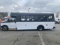 A 2018 Chevrolet Express bus with a white body and black roof featuring large windows and a ramp on the side