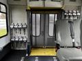 A 2016 Ford Econoline interior featuring a grey driver's seat and silver handrails mounted on the walls with a mesh barrier and a yellow step platform at the entrance