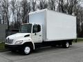 A white 2006 Hino 268 box truck with a large empty cargo area and a front cab featuring a prominent grille and headlights