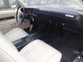 Interior of a 1974 Dodge Challenger featuring white bucket seats a black dashboard and a wooden gear shift knob