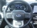 Steering wheel of a 2022 Ford F-150 with control buttons and Ford logo visible on a modern dashboard display