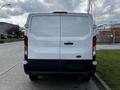 A 2018 Ford Transit cargo van viewed from the rear with a white exterior and dual rear doors