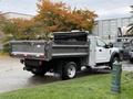 A 2021 Ford F-550 with a flatbed design parked with its bed in an upright position showing a metallic finish and black wheels