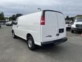 A white 2013 Chevrolet Express cargo van with no side windows and chrome wheels parked facing right