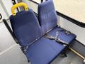 A blue upholstered bench seat with a yellow handle and a black seatbelt attached sitting in a vehicle