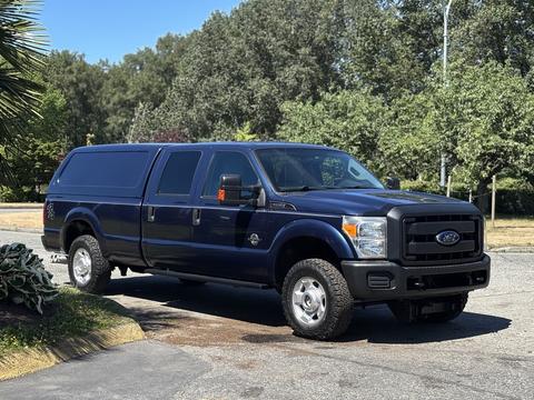 2014 Ford F-250 SD in navy blue with a truck bed cap parked with four-wheel drive tires and a spacious cab