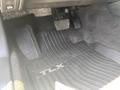The floor of a 2017 Acura TLX featuring rubber floor mats with "TLX" branding and visible gas and brake pedals