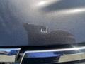 A close-up view of the hood of a 2016 Chevrolet Tahoe showing a scratch and some faint markings on the dark metallic paint
